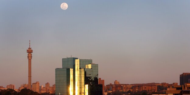 Eine Stadtsilhouette mit darüberstehendem Mond Eine Stadtsilhouette mit darüberstehendem Mond