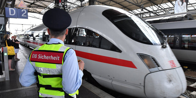 Ein Sicherheitsmitarbeiter mit einer neongelben Weste steht vor einem ICE Ein Sicherheitsmitarbeiter mit einer neongelben Weste steht vor einem ICE