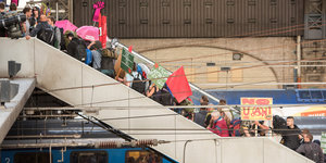 Menschen in schwarzer Kleidung mit Transparent und roter Flagge auf einer Treppe