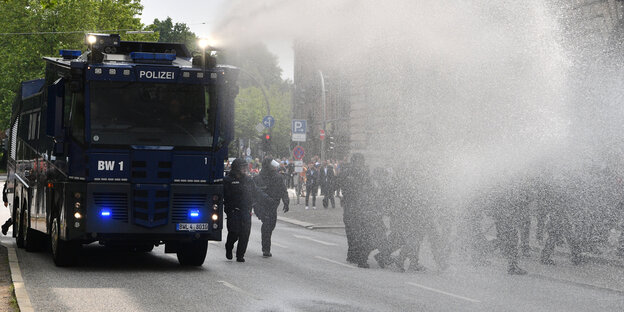 Ein blauer Wasserwerfer spritzt Wasser auf der Straße Ein blauer Wasserwerfer spritzt Wasser auf der Straße