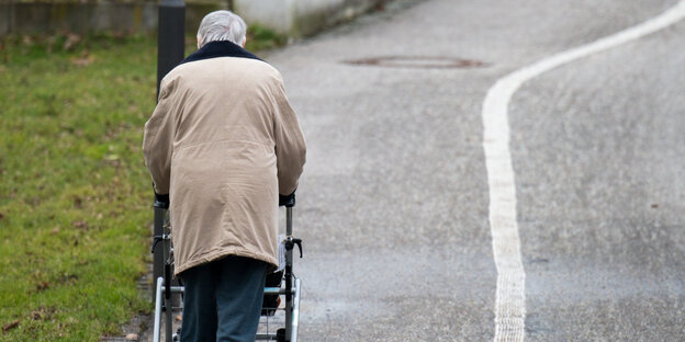 Eine Person mit Rollator läuft auf der Straße Eine Person mit Rollator läuft auf der Straße