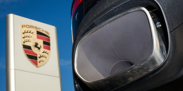 ein Auspuff, im Hintergrund das Porsche-Logo