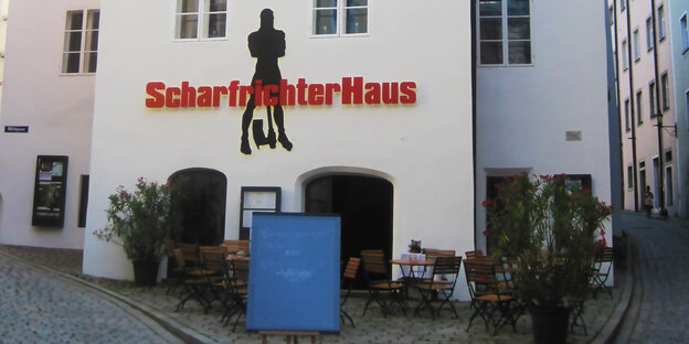 Auf einer Fassade steht „Scharfrichterhaus“. Davor sind Tische und Stühle aufgestellt Auf einer Fassade steht „Scharfrichterhaus“. Davor sind Tische und Stühle aufgestellt