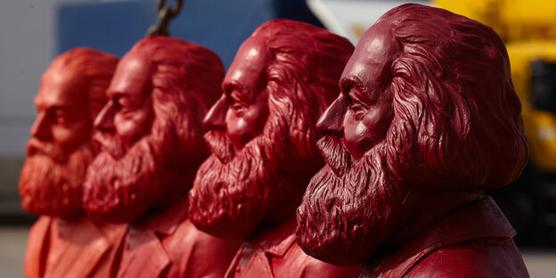 Vier rote Marxbüsten nebeneinander im Halbprofil Vier rote Marxbüsten nebeneinander im Halbprofil
