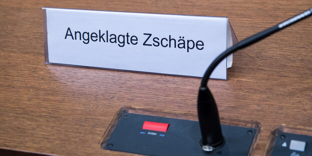 Neben einem Tischmikrofon ein Platzschild mit der Aufschrift „Angeklagte Zschäpe“ Neben einem Tischmikrofon ein Platzschild mit der Aufschrift „Angeklagte Zschäpe“