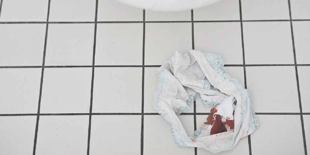 Eine Unterhose mit Blutflecken liegt auf weißen Fliesen Eine Unterhose mit Blutflecken liegt auf weißen Fliesen