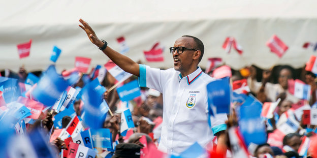 Ruandas Präsident Paul Kagame winkt Menschen mit Fähnchen zu