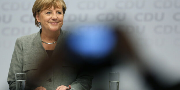 Eine Frau lacht. Vor ihr hält jemand ein Handy hoch und macht ein Bild von ihr Eine Frau lacht. Vor ihr hält jemand ein Handy hoch und macht ein Bild von ihr