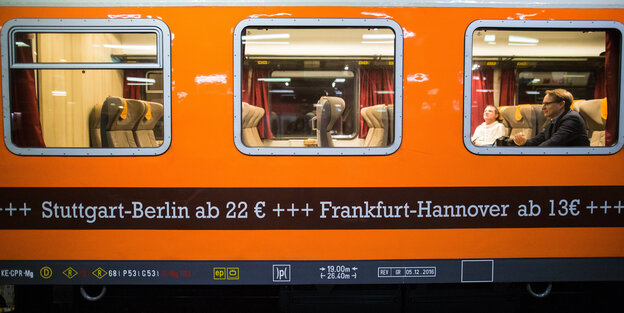 In einem orangenfarbenen Zugabteil sieht man zwei Reisende, auf dem Zugabteil steht "Stuttgart-Berlin 22 Euro / Frankfurt-Hannover 13 Euro" In einem orangenfarbenen Zugabteil sieht man zwei Reisende, auf dem Zugabteil steht "Stuttgart-Berlin 22 Euro / Frankfurt-Hannover 13 Euro"
