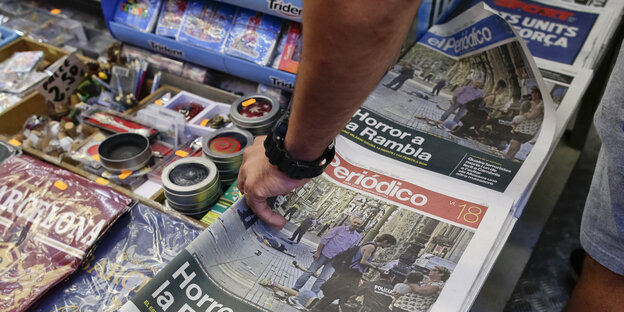Eine Hand greift nach Zeitungen Eine Hand greift nach Zeitungen