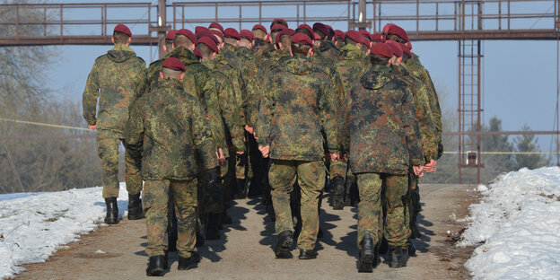 Eine Truppe Soldaten marschiert, man sieht sie von hinten. Es liegt Schnee.