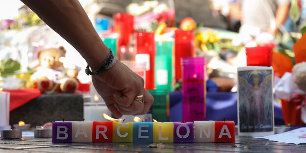 Hand zündet eine Kerze an, davor die Aufschrift "Barcelona" Hand zündet eine Kerze an, davor die Aufschrift "Barcelona"