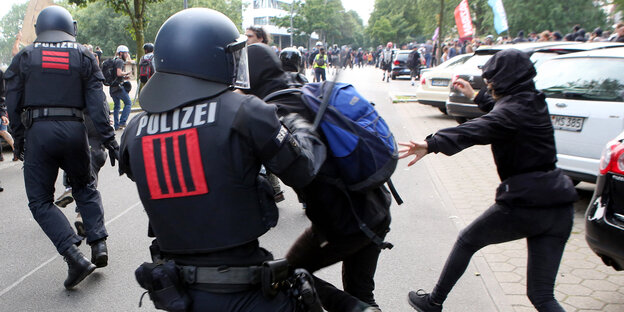 Ein Polizist hält einen Demonstranten am Arm fest und setzt seinen Schlagstock ein Ein Polizist hält einen Demonstranten am Arm fest und setzt seinen Schlagstock ein