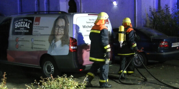 Feuerwehrleute laufen abends an einem Fahrzeug vorbei. Auf dem Auto: das Konterfei der Politikerin Michelle Müntefering Feuerwehrleute laufen abends an einem Fahrzeug vorbei. Auf dem Auto: das Konterfei der Politikerin Michelle Müntefering