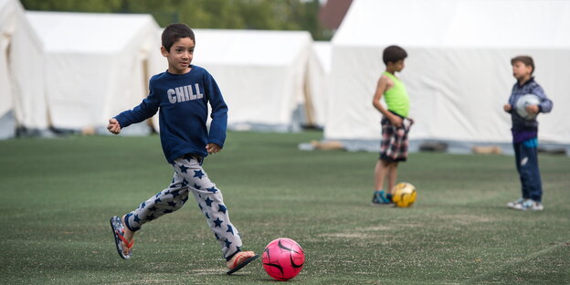 Drei Kinder spielen mit Bällen zwischen Zelten Drei Kinder spielen mit Bällen zwischen Zelten