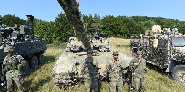 Soldaten stehen neben Panzern, das Panzerrohr ragt in die Kamera Soldaten stehen neben Panzern, das Panzerrohr ragt in die Kamera