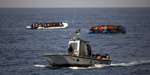 zwei Flüchtlingsboote und ein Schiff im Meer zwei Flüchtlingsboote und ein Schiff im Meer