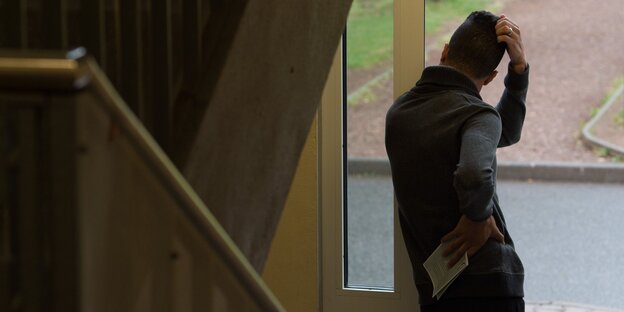 Ein Mann lehnt an einem Geländer un kratzt sich am Kopf Ein Mann lehnt an einem Geländer un kratzt sich am Kopf