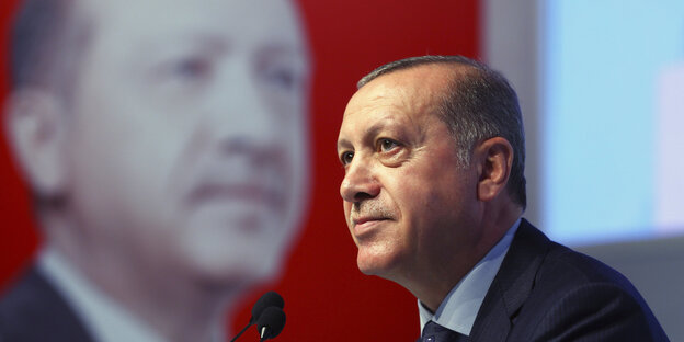 Erdogan steht vor einem überlebensgroßen Bild von Erdogan und spricht in ein Mikro Erdogan steht vor einem überlebensgroßen Bild von Erdogan und spricht in ein Mikro