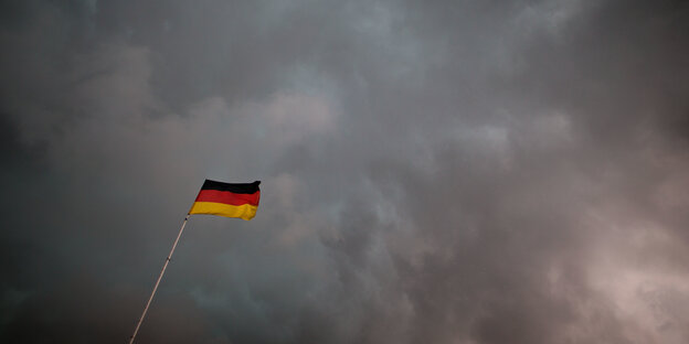 Eine Deutschlandfahne vor dunklen Wolken Eine Deutschlandfahne vor dunklen Wolken