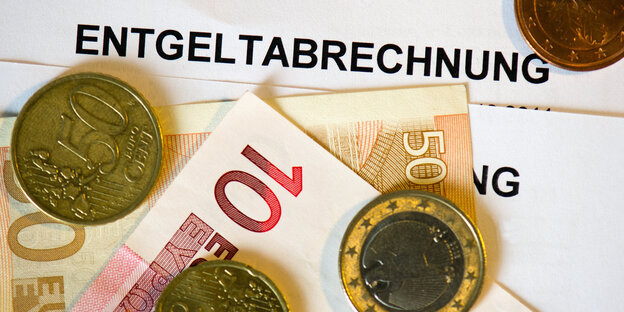 Euro-Scheine und -Münzen liegen auf einem Zettel, auf dem Entgeltabrechnung steht Euro-Scheine und -Münzen liegen auf einem Zettel, auf dem Entgeltabrechnung steht