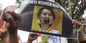 Karikatur von Suu Kyi auf einem Demo-Plakat