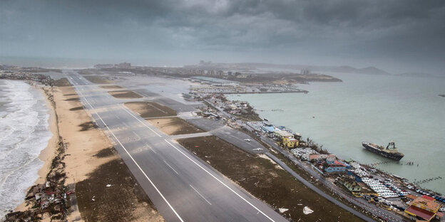 Eine Straße trennt zwei Küsten auf der Antilleninsel Sint Maarten, die Wolken darüber deuten stürmisches Wetter an Eine Straße trennt zwei Küsten auf der Antilleninsel Sint Maarten, die Wolken darüber deuten stürmisches Wetter an