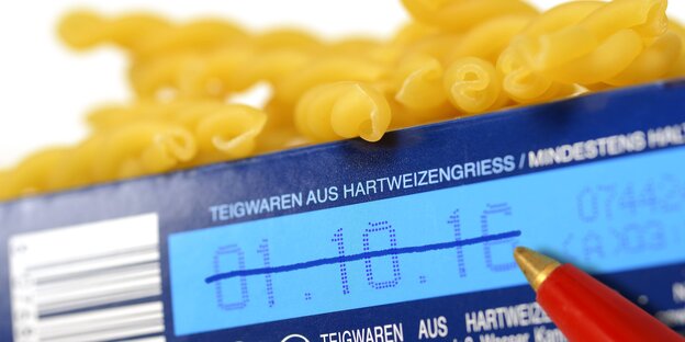 ein Kugelschreiber streicht das Haltbarkeitsdatum auf einer Nudelpackung durch. Ober quillen ein paar Nudeln heraus. ein Kugelschreiber streicht das Haltbarkeitsdatum auf einer Nudelpackung durch. Ober quillen ein paar Nudeln heraus.