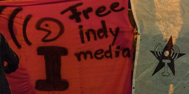 Ein rotes Transparent, auf dem „Free indymedia“ steht Ein rotes Transparent, auf dem „Free indymedia“ steht