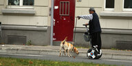 Ein Mann auf einem Segway, daneben ein Hund, den er an der Leine hält