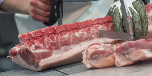 Jemand zerschneidet ein großes Stück Schweinekamm Jemand zerschneidet ein großes Stück Schweinekamm