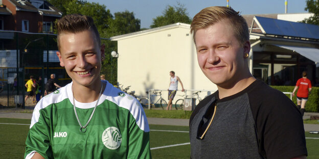 Marino und Fabian stehen lächelnd auf dem Fußballplatz