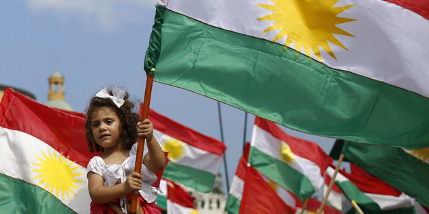 Ein kleines Mädchen hält eine kurdische Flagge