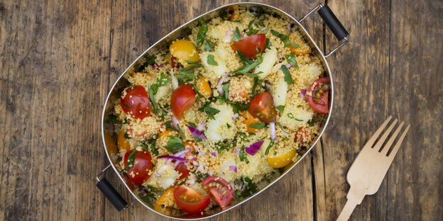 Ein Gefäß mit Couscous und eine Gabel Ein Gefäß mit Couscous und eine Gabel
