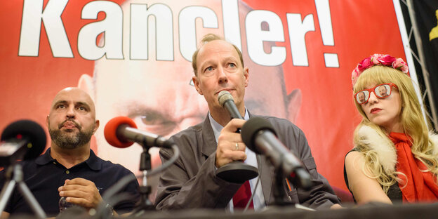 Politiker der Satirepartei vor "Kancler"-Plakat Politiker der Satirepartei vor "Kancler"-Plakat