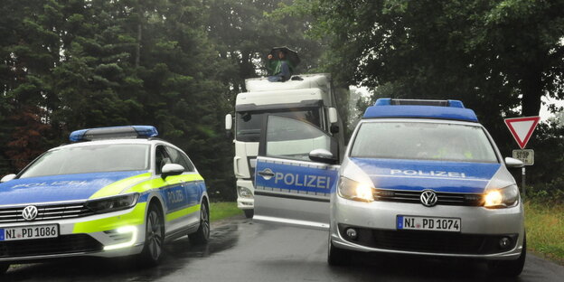 Ein Mann sitzt auf einem LKW und hindert diesen so daran weiterzufahren. Davor ist Polizei zu sehen Ein Mann sitzt auf einem LKW und hindert diesen so daran weiterzufahren. Davor ist Polizei zu sehen