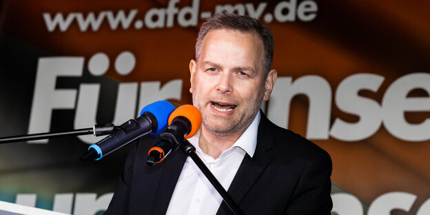 Ein Mann spricht auf einem Podium in ein Mikrofon Ein Mann spricht auf einem Podium in ein Mikrofon