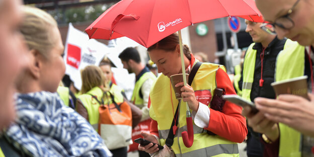Air-Berlin-Mitarbeiterinnen mit rotem Schirm und Warnwesten protestieren Air-Berlin-Mitarbeiterinnen mit rotem Schirm und Warnwesten protestieren