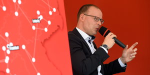 Matthias Höhn, Bundesgeschäftsführer der Linken, mit Mikro vor rotem Hintergrund