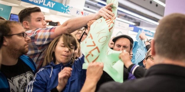 Menschen rangeln, einer hat ein Plakat in der Hand, das halb zerrissen ist