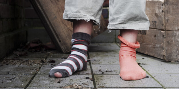 Kinderbeine in einer Hose und löchrigen Socken Kinderbeine in einer Hose und löchrigen Socken