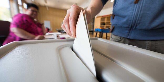 Wahlunterlagen werden in eine Wahlurne gesteckt Wahlunterlagen werden in eine Wahlurne gesteckt