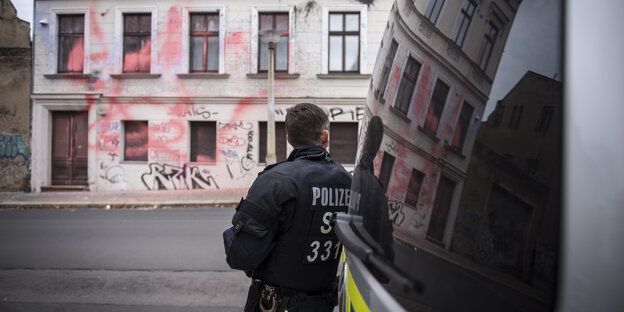 Ein Polizist steht vor einem Haus mit Farbklecksen