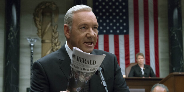 Mann vor der US-Fahne, es ist Kevin Spacey in seiner Rolle als US-Präsident in der TV-Serie "House of Cards" Mann vor der US-Fahne, es ist Kevin Spacey in seiner Rolle als US-Präsident in der TV-Serie "House of Cards"