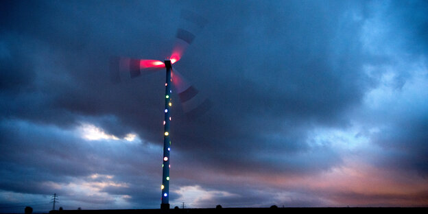ein Windrad bei Nacht mit Lichtern an den Flügeln ein Windrad bei Nacht mit Lichtern an den Flügeln