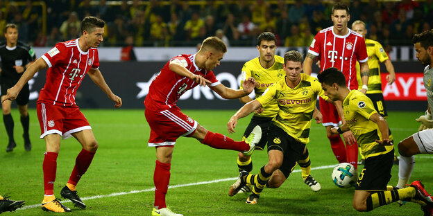 Spieler in gelben und roten Trikots kämpfen auf dem Spielfeld um einen Ball Spieler in gelben und roten Trikots kämpfen auf dem Spielfeld um einen Ball