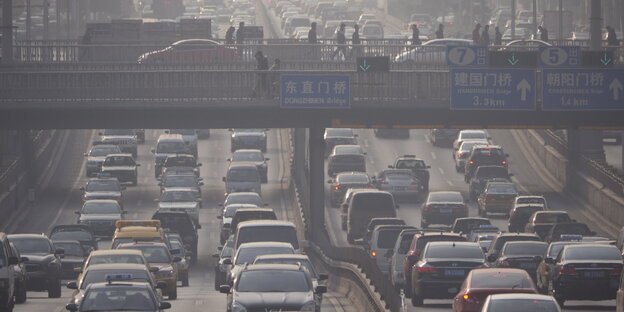 eine breite Straße, auf der sich Autos stauen, die Luft ist vernebelt