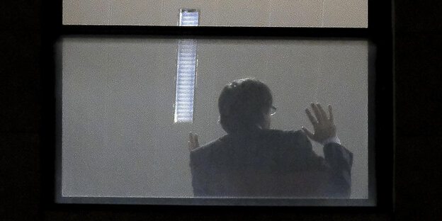 Ein Mann, vermutlich Carles Puigdemont, von hinten: Er sitzt an einem Fenster und gestikuliert Ein Mann, vermutlich Carles Puigdemont, von hinten: Er sitzt an einem Fenster und gestikuliert