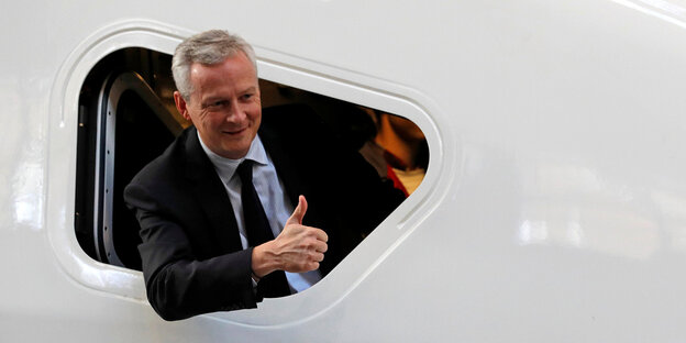 Frankreichs Finanzminister Bruno Le Maire guckt auf einem Flugzeug und zeigt Daumen hoch Frankreichs Finanzminister Bruno Le Maire guckt auf einem Flugzeug und zeigt Daumen hoch