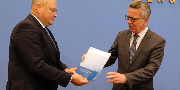 Ein Mann überreicht einem anderen einen Bericht Ein Mann überreicht einem anderen einen Bericht